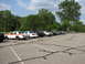 2003 Ford Crown Victoria - A line of cars, including a 2003 Ford Crown Victoria, are parked in a lot on a sunny day.