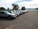 2003 Ford Crown Victoria - A line of silver Ford Crown Victorias are parked by a lake on a sunny day.