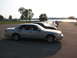 2003 Ford Crown Victoria - Several cars are parked in a lot near a body of water on a sunny day.