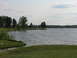 2003 Ford Crown Victoria - A wide view of a lake on a cloudy day, with trees lining the distant shore and a small boat visible on the water.