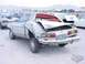 1978 Ford Mustang II - This severely damaged sedan is parked in a lot with other vehicles under a bright sky.