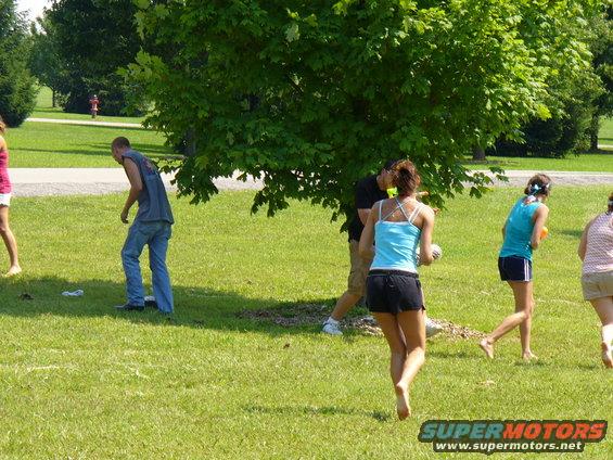 People playing in a grassy park with trees