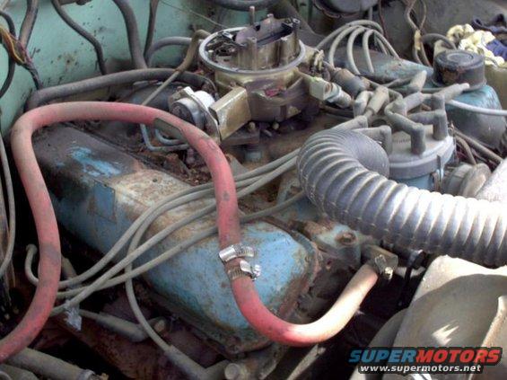 Engine bay with a blue engine block, red hose, and black ribbed hose. The engine appears old and rusty
