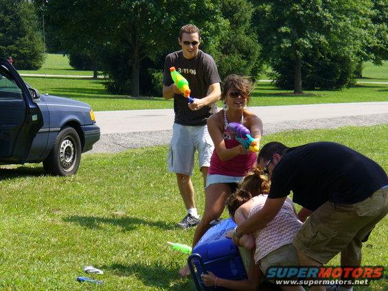 People with water guns in a park, one person is on the ground