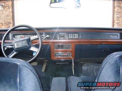 Dashboard and steering wheel of a car, showing wood trim and blue upholstery