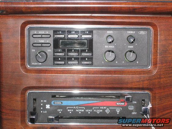 Close-up of car dashboard showing Ford radio and climate controls with wood grain trim