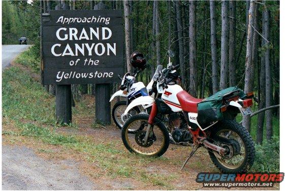 Two dirt bikes parked next to a sign reading 'Approaching GRAND CANYON of the Yellowstone'