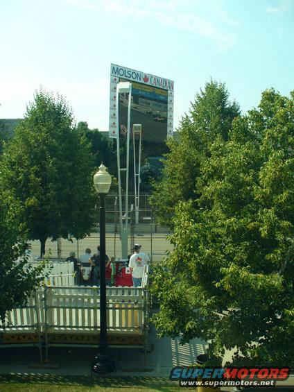Jumbotron screen showing race cars, Molson Canadian branding, trees, and people