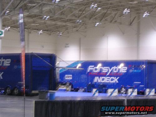 Two blue racing trailers with 'Forsythe' and 'INDECK' logos are parked indoors