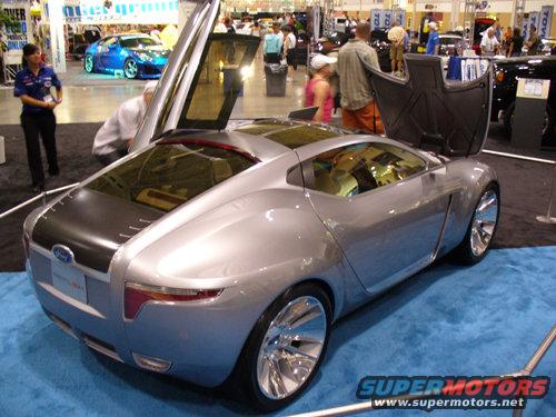 Silver concept car with gullwing doors open, Ford badge visible on rear