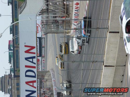 Race cars on a track with Canadian branding. One car is white with blue stripes
