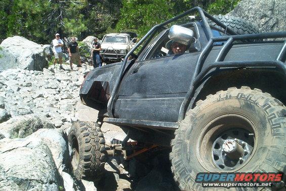 Black off-road vehicle with roll cage navigating rocky terrain