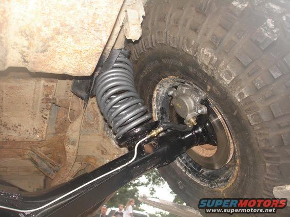 Close-up of a large coil spring and brake caliper on an off-road vehicle's suspension system