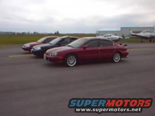 Red 1998 Ford Taurus in the foreground, with two other sedans behind it on an airfield