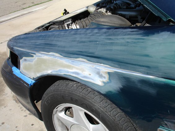 1995 Ford Taurus fender with body filler and blue tape, showing exposed metal and primer
