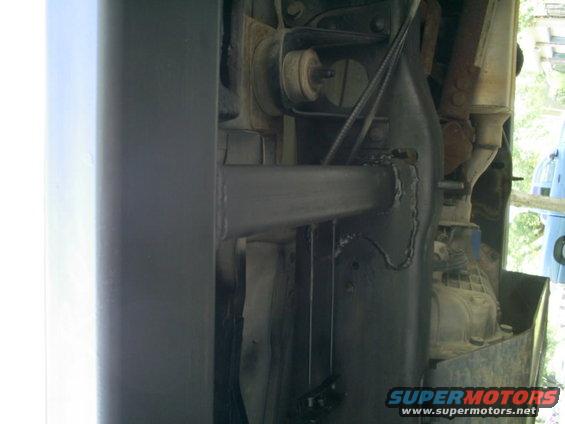 Underside view of vehicle frame with suspension components and exhaust pipe visible. Supermotors.net logo in corner