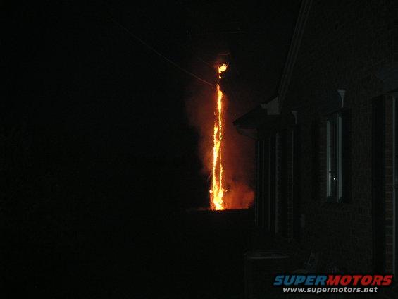 Fire erupting from a power line at night next to a brick building