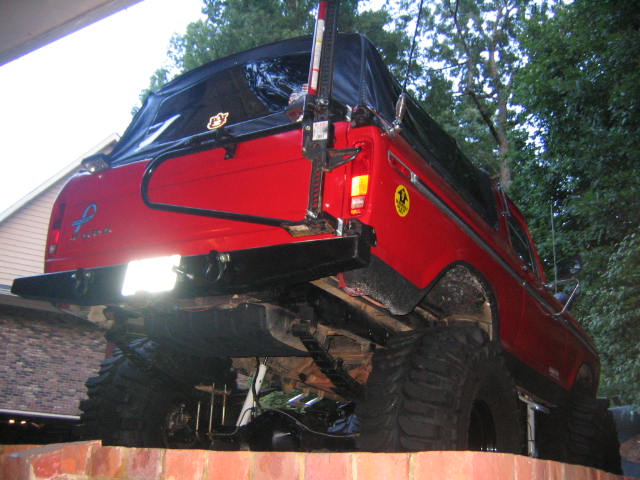 Red lifted SUV with a soft top, lifted high on large tires. The rear of the vehicle is visible