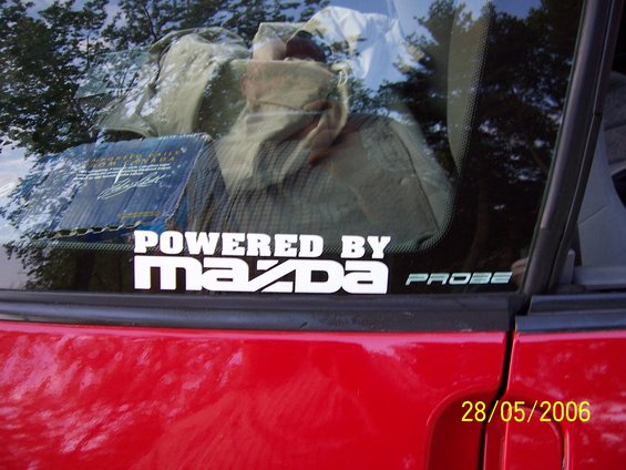 Red car side view with "POWERED BY MAZDA PROBE" sticker on window