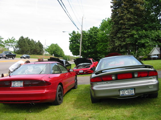Rear view of a silver 1996 Ford Probe and a red 1996 Ford Probe, with other cars visible in the background