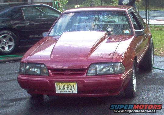 Red coupe with a big hood, parked next to a black car. New Jersey plate UJN-80A