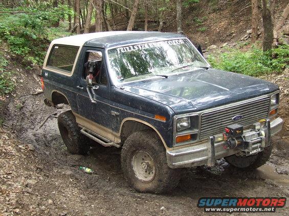 1986 Ford Bronco off-roading, dark blue with white top, winch on front bumper