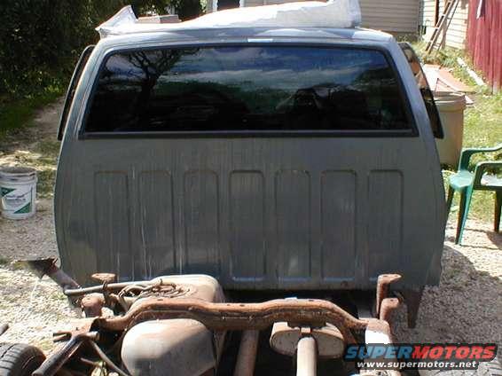 Rear of a gray pickup truck cab with a large window and ribbed bed paneling