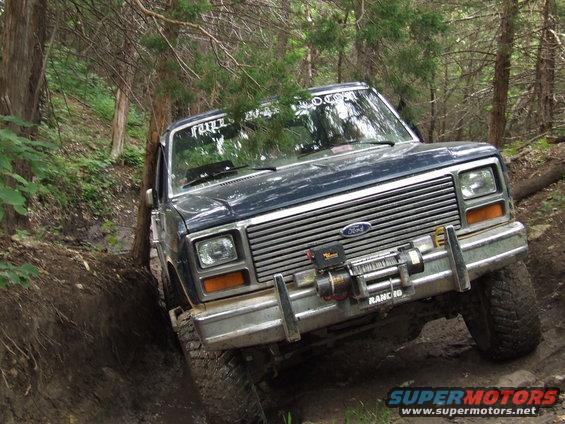 1986 Ford Bronco navigating a wooded trail, front winch visible