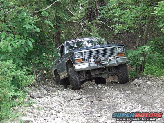 Dark blue Ford Bronco with a winch, driving on a rocky trail