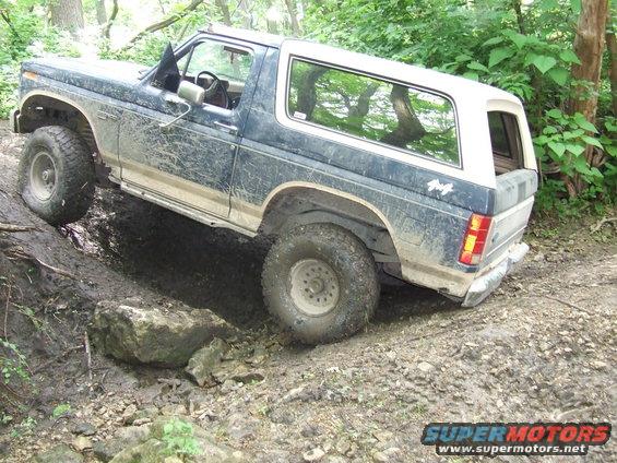 1986 Ford Bronco 3q-front view off-roading on a muddy trail