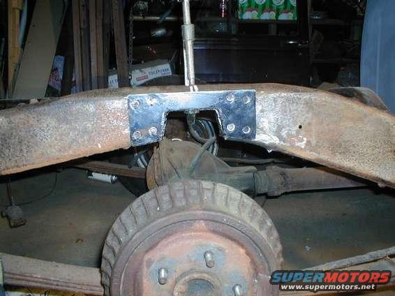 Rusted vehicle frame with a welded metal bracket, rear axle, and drum brake