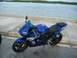 2003 Yamaha R1 - A blue Yamaha R6 motorcycle is parked on a paved surface next to a body of water.