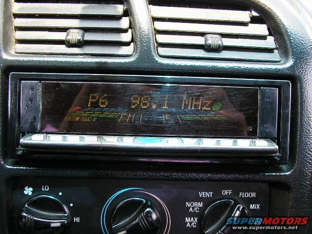 Car interior showing an aftermarket radio display and climate control knobs. Radio shows 'P6 98.1 MHZ'