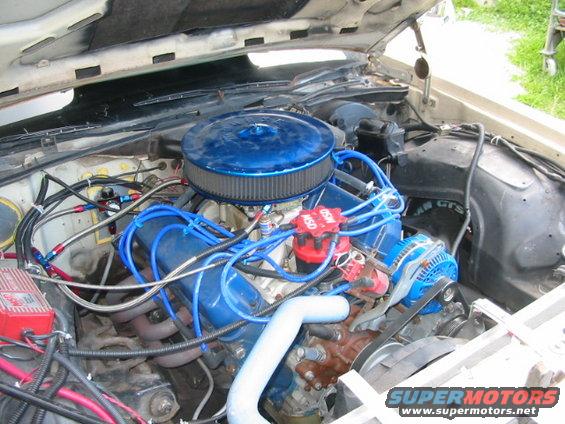 Engine bay with blue air filter, MSD distributor, and blue spark plug wires. Some parts are rusty