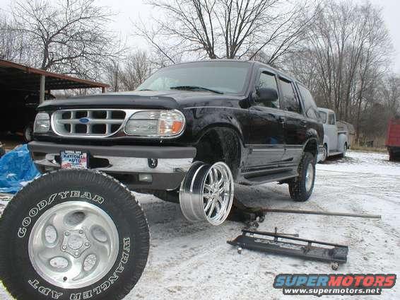 Black 1998 Ford Explorer SUV with one wheel removed, jacked up