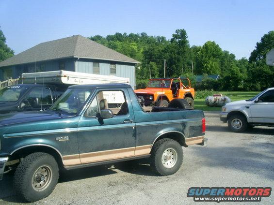 Green Ford Bronco parked next to an orange Jeep and a white truck