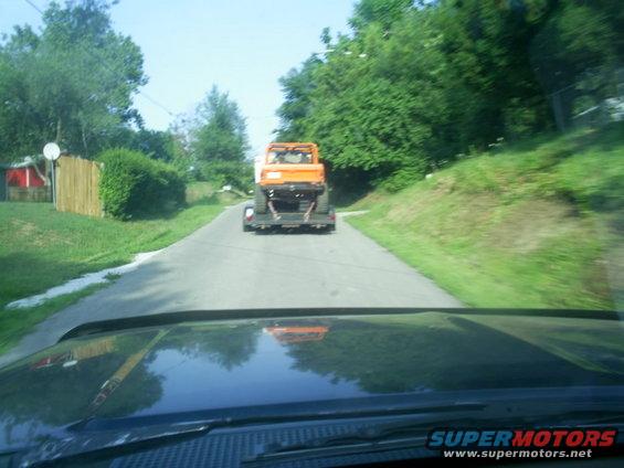 Orange vehicle on a trailer being towed on a road