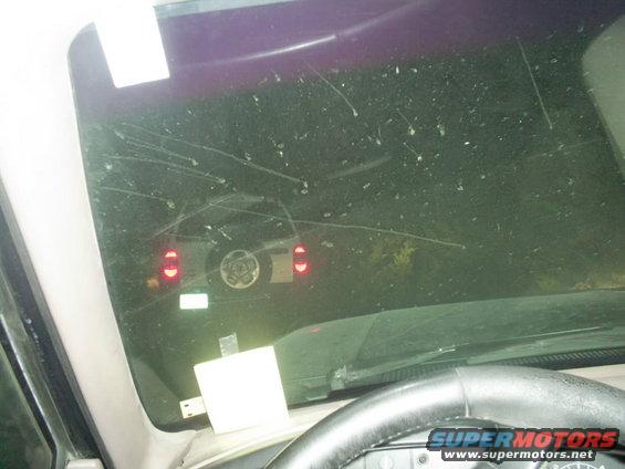 Rear view of dark SUV with spare tire, seen through a dirty windshield