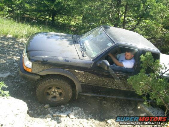 Black Ford Ranger pickup truck driving off-road, driver visible