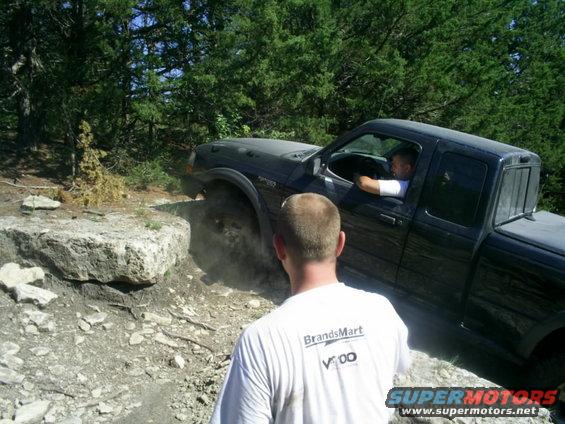 Black pickup truck with a man driving, navigating a rocky incline