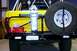 1984 Ford Bronco - Rear view of a yellow SUV equipped with a spare tire, jack, and auxiliary fuel can.