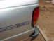 1994 Mazda B3000 - The rear side of a silver pickup truck shows a blue 'SE' decal and scuffs near the taillight.