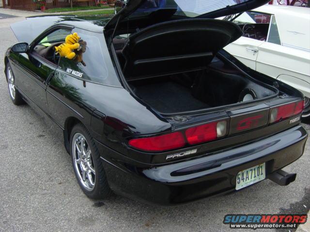 Black 1995 Ford Probe with open trunk and hood, plush toy on passenger seat. License plate 54A7101