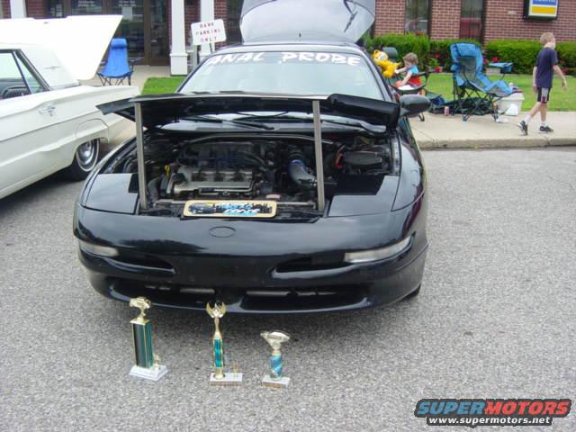 Black 1995 Ford Probe with hood open, displaying trophies in front