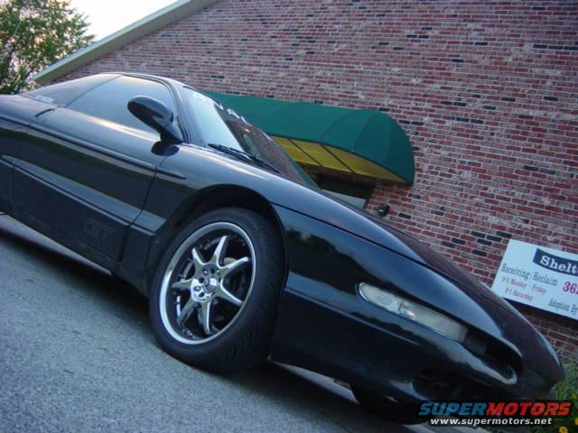 black sports coupe parked outside brick building with green awning