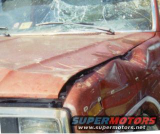 Red 1980s Ford F-150 with significant front-end damage, including a cracked windshield and dented hood