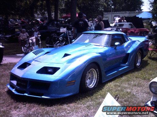 Blue sports car with a wide body kit and aggressive styling, parked on grass
