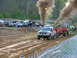 2000 Ford F-250 - A truck competes in a pull event, generating significant exhaust smoke as it drags a weighted sled across a dirt track.