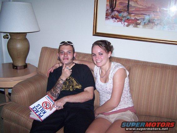 Couple sitting on a couch, man holding a book titled "Peace Kills"