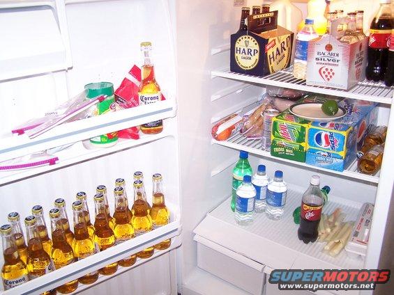 Refrigerator interior stocked with Corona, Harp Lager, Pepsi, and Coca-Cola bottles and cans
